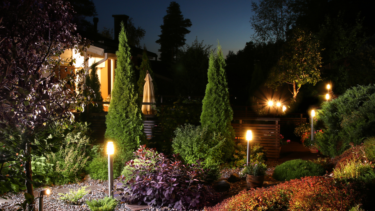 A garden at night with lit candles in the bushes