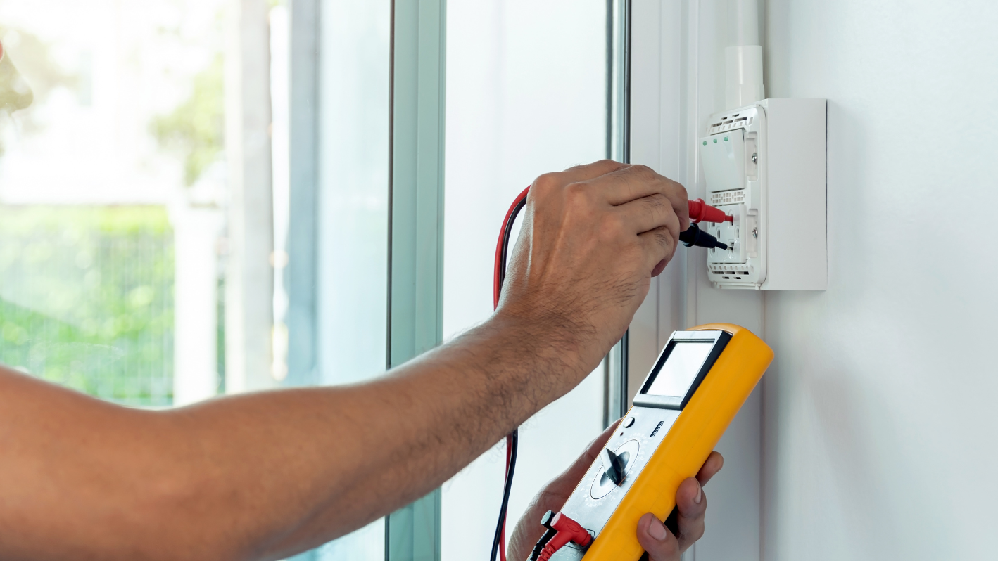 A man working on a wall with a multimeter